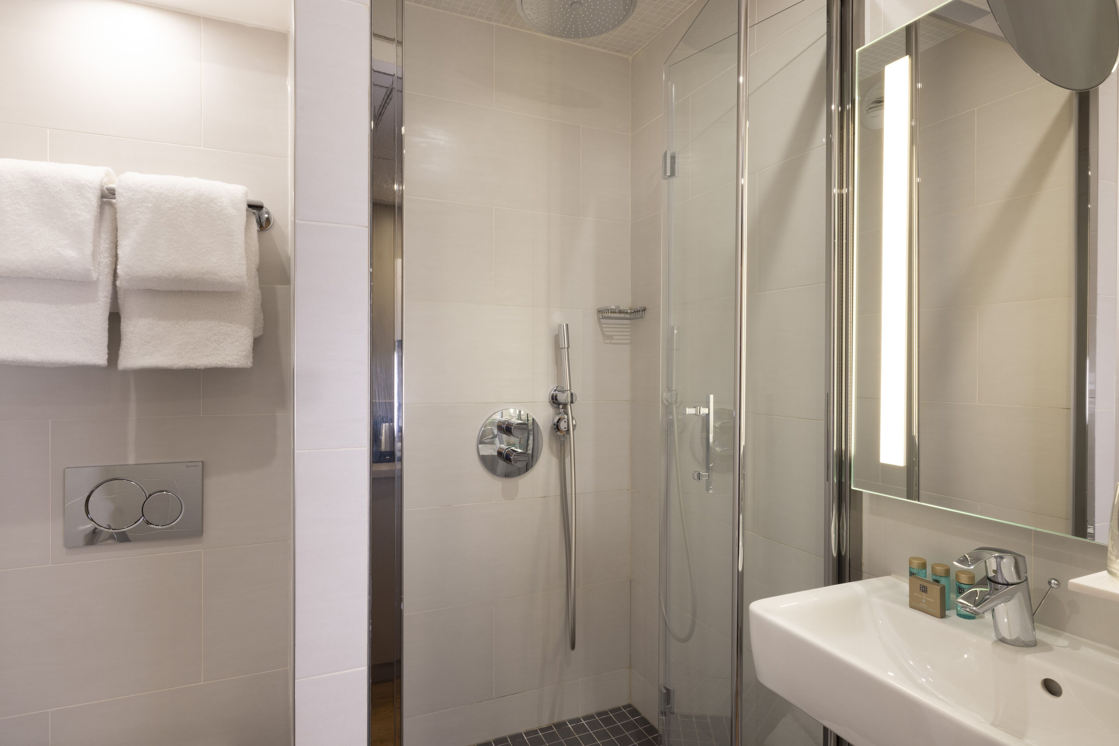 A modern bathroom with a glass shower enclosure, a white sink, and a mirror.