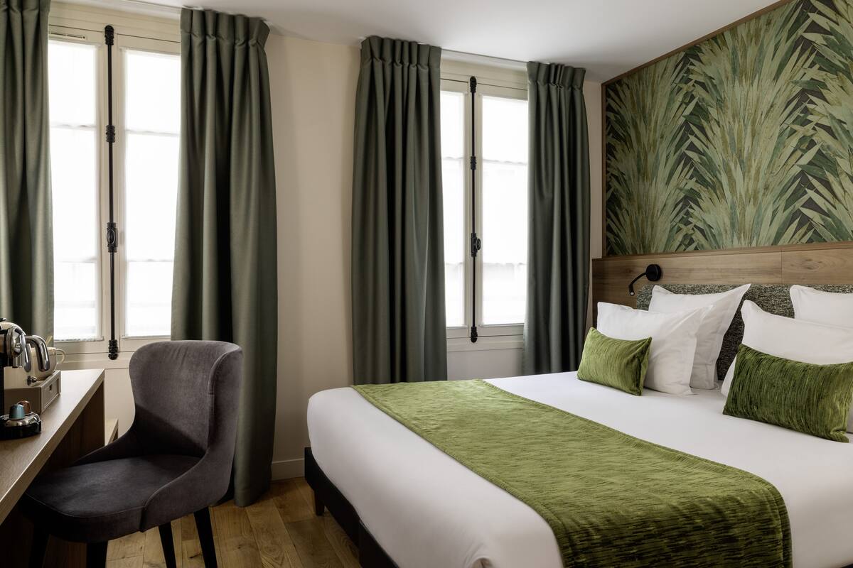 Quarto de hotel com cama, escrivaninha e cadeira.