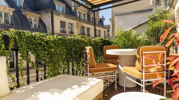 A balcony with a white sofa, two chairs, and a table.