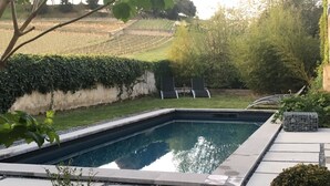 A rectangular swimming pool with a paved deck, surrounded by a low hedge and a grassy area. - Clos 1906 (Saint-Émilion)