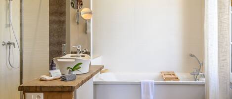 Un baño moderno con tocador de madera, bañera y zona de ducha.