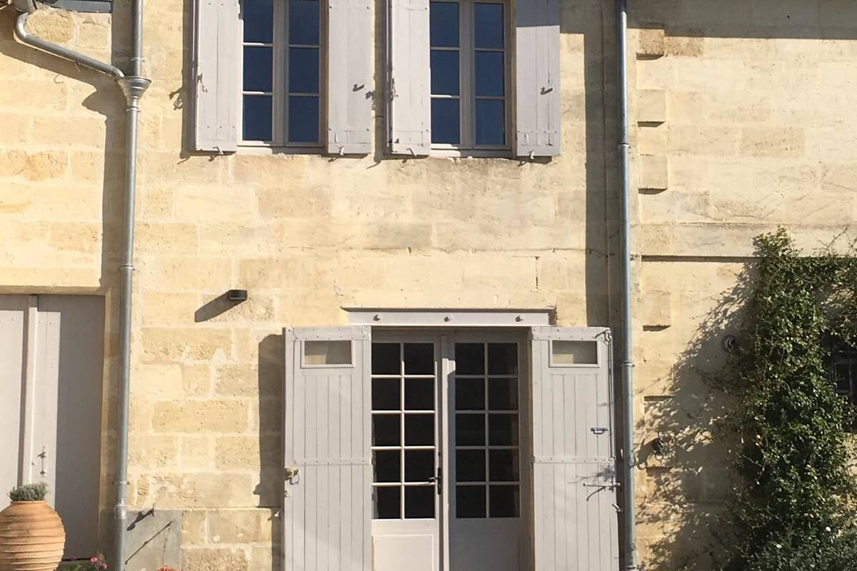 Ein zweistöckiges Gebäude mit rotem Ziegeldach, weißen Fensterläden und einem zentralen Eingang mit einer Glastür.