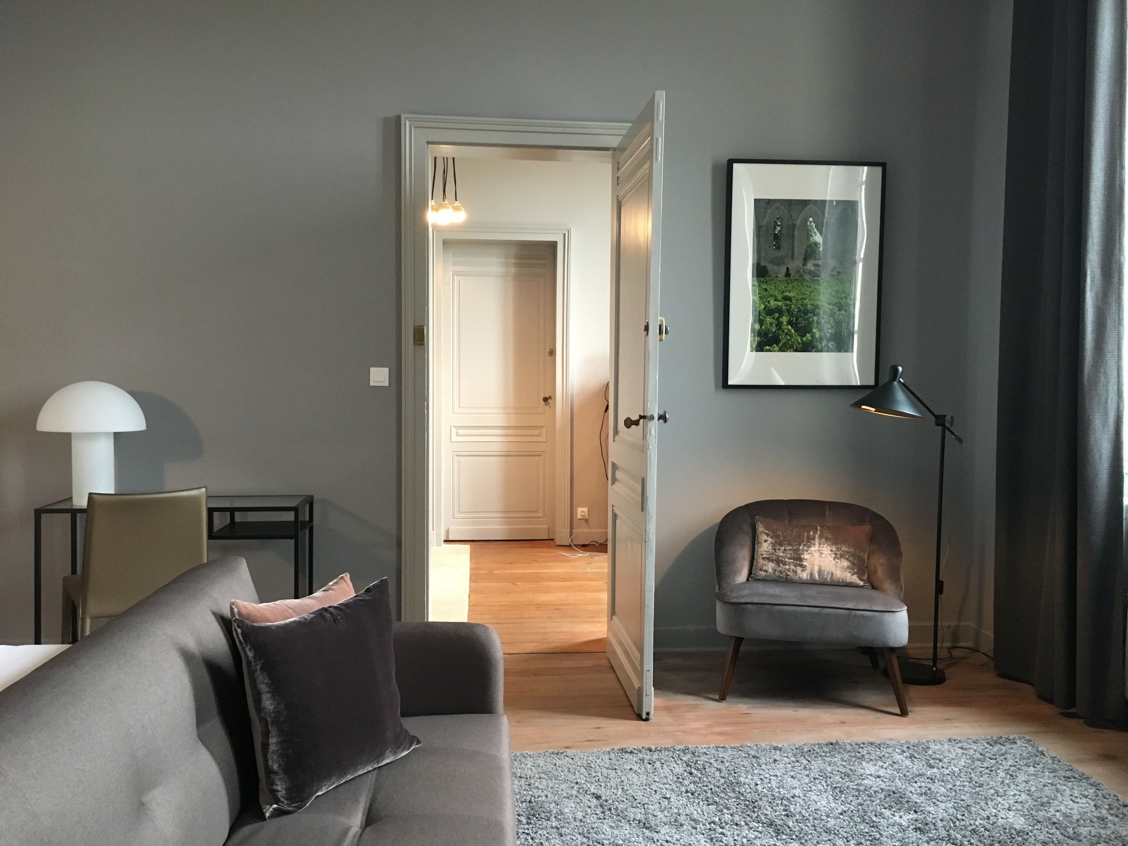 Una sala de estar moderna con un sofá gris, una mesita auxiliar, una lámpara de pie y un cuadro enmarcado en la pared.