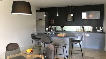 A modern kitchen with a central island, bar stools, and a dining table with chairs.