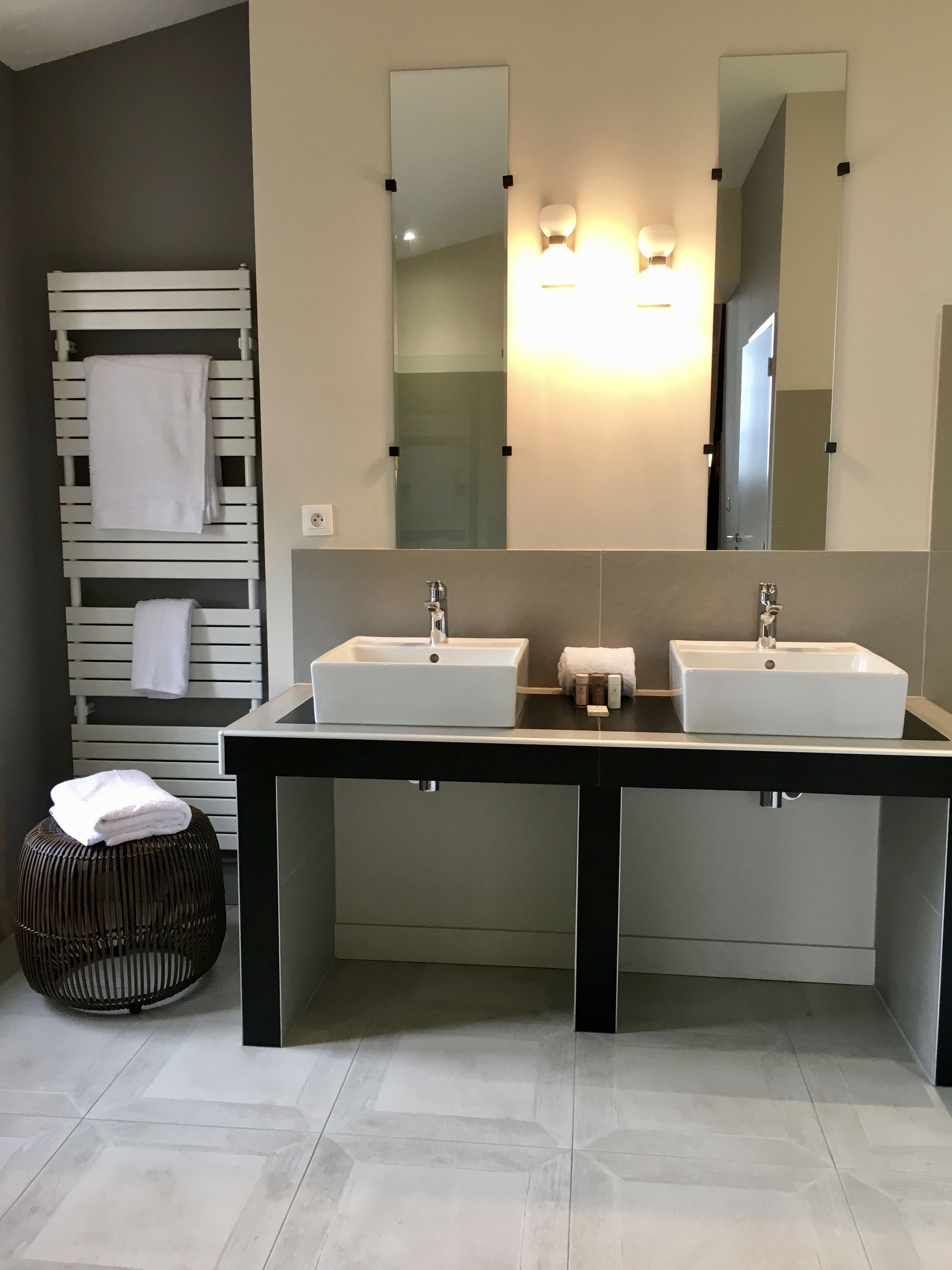 Un baño moderno con dos lavamanos, un espejo grande y un perchero con toallas.