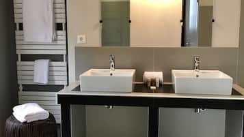 Un baño moderno con dos lavamanos, un espejo grande y un perchero con toallas.