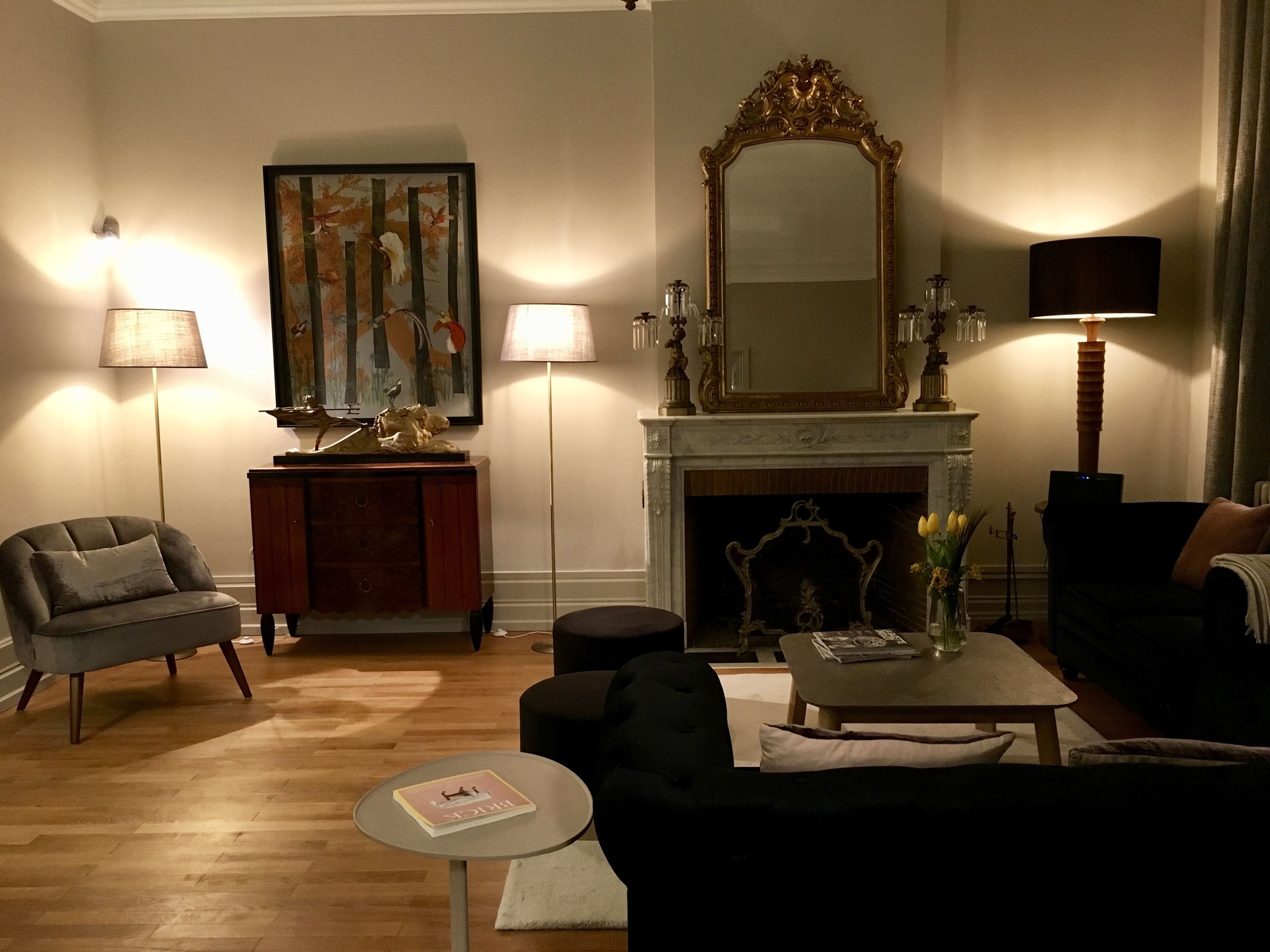 Una sala de estar con chimenea, un espejo grande y una araña.