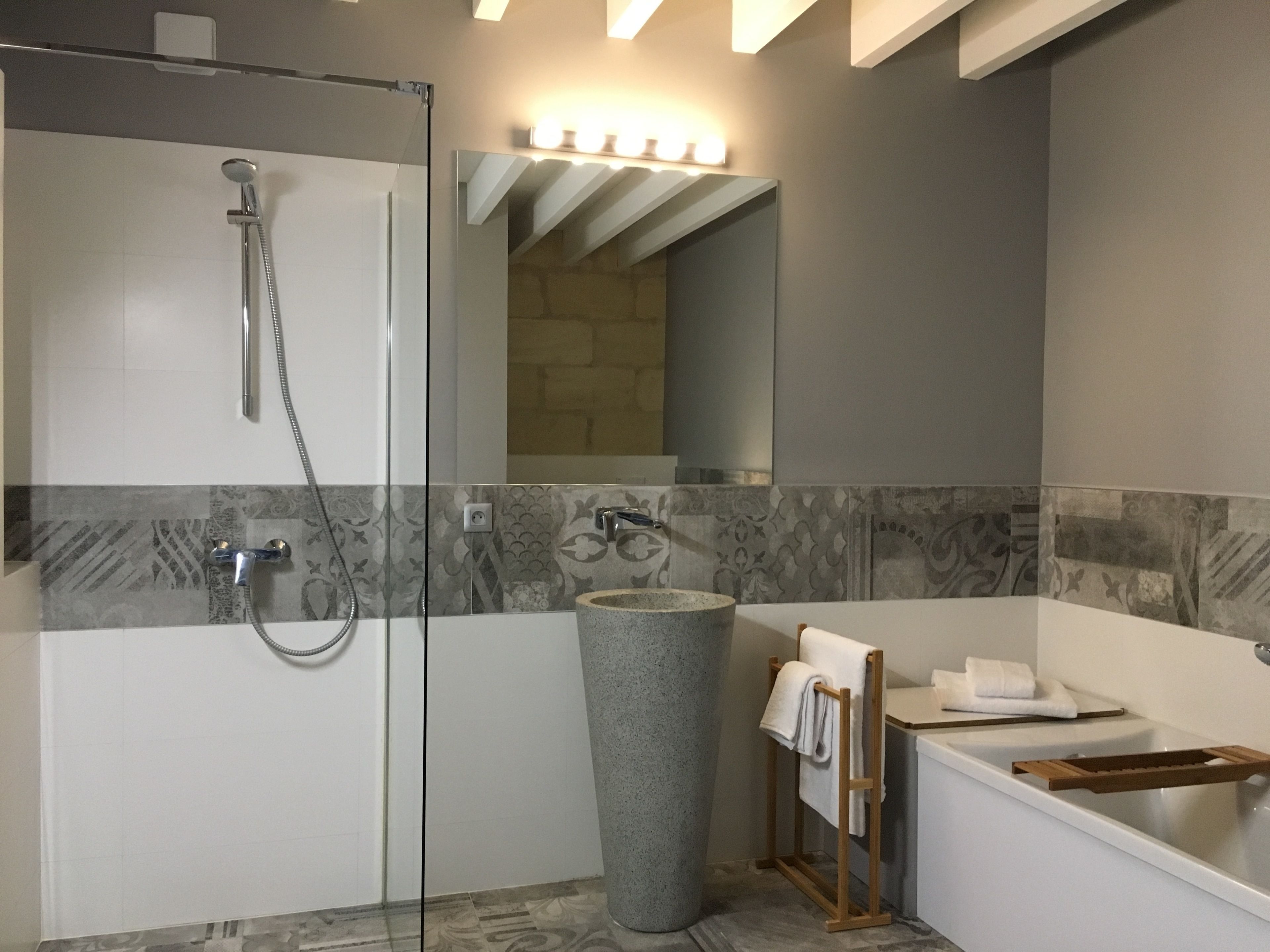A modern bathroom with a glass-enclosed shower, a freestanding bathtub, and a stone accent wall.