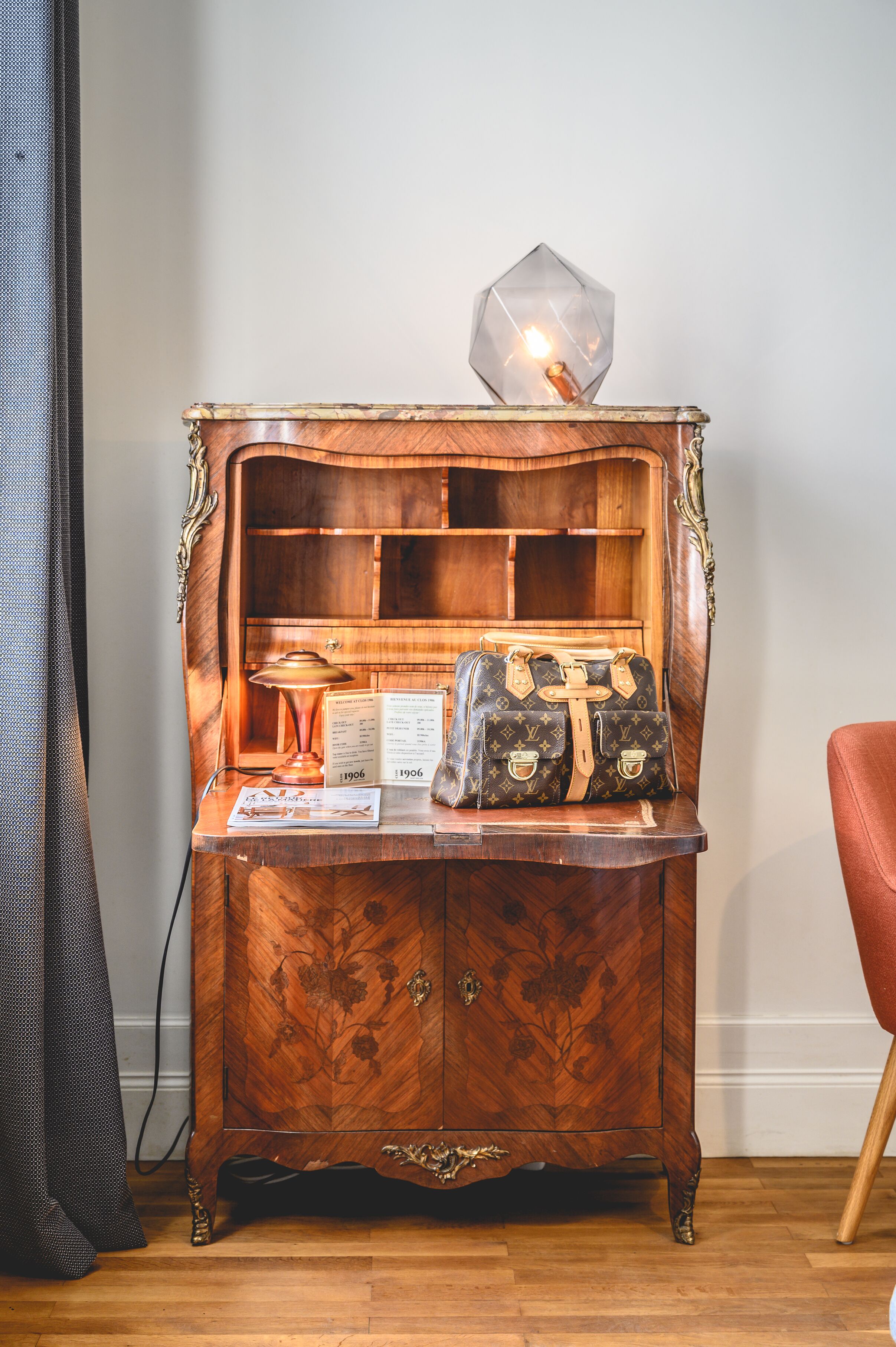 A wooden cabinet with a lamp, a Louis Vuitton bag, and a menu.