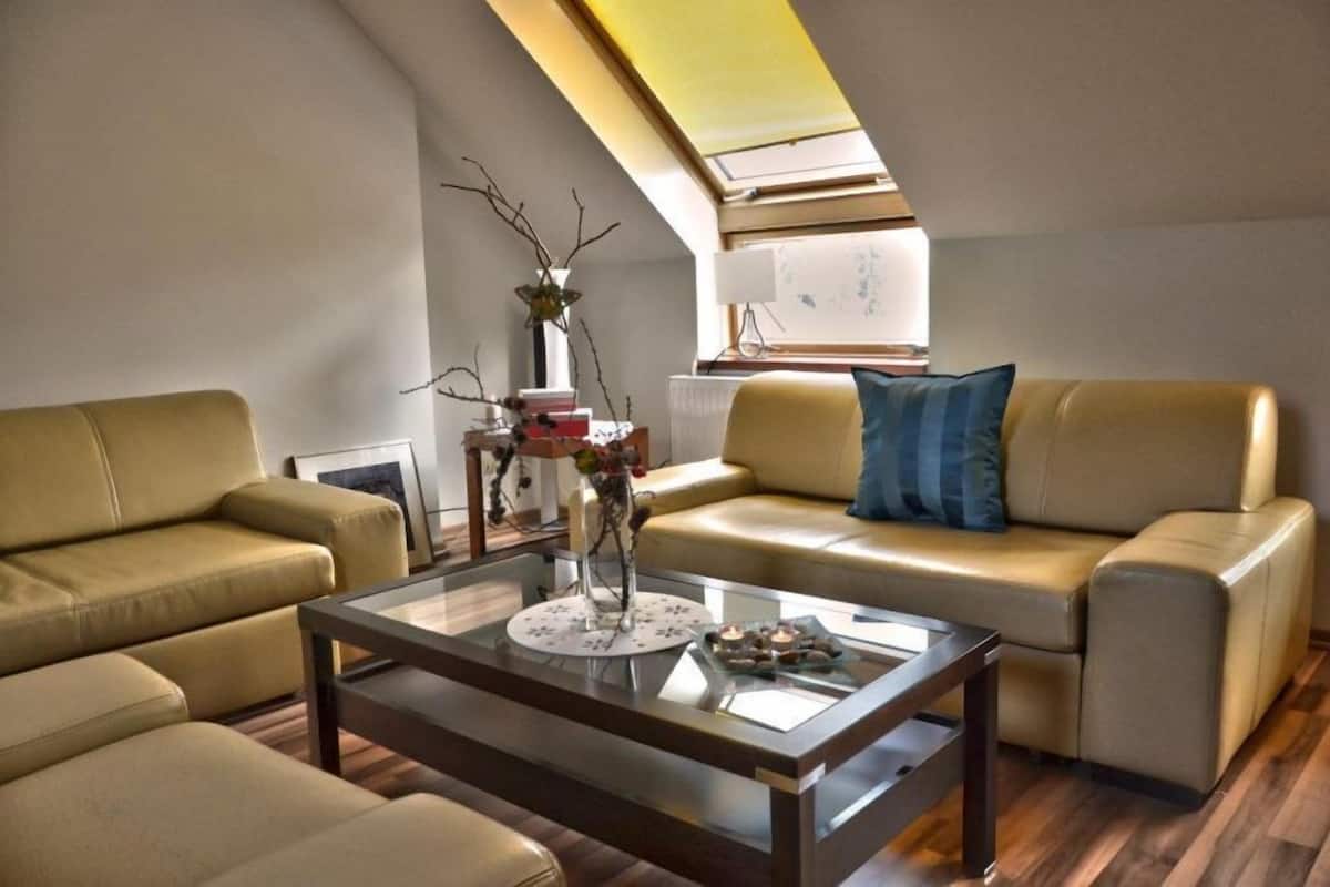 Un salon moderne avec une table basse en verre, deux canapés beige et une lucarne.