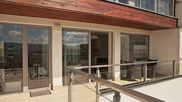 A modern building with a wooden balcony, glass doors, and a tiled floor.