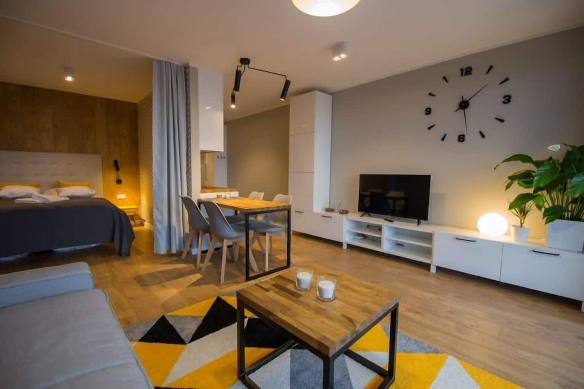 Une chambre d’hôtel moderne équipée d’un lit, d’un coin repas, d’une télévision et d’une horloge murale.