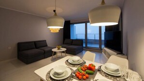 Una sala de estar moderna con comedor, dos sofás, una mesita redonda y un televisor.
