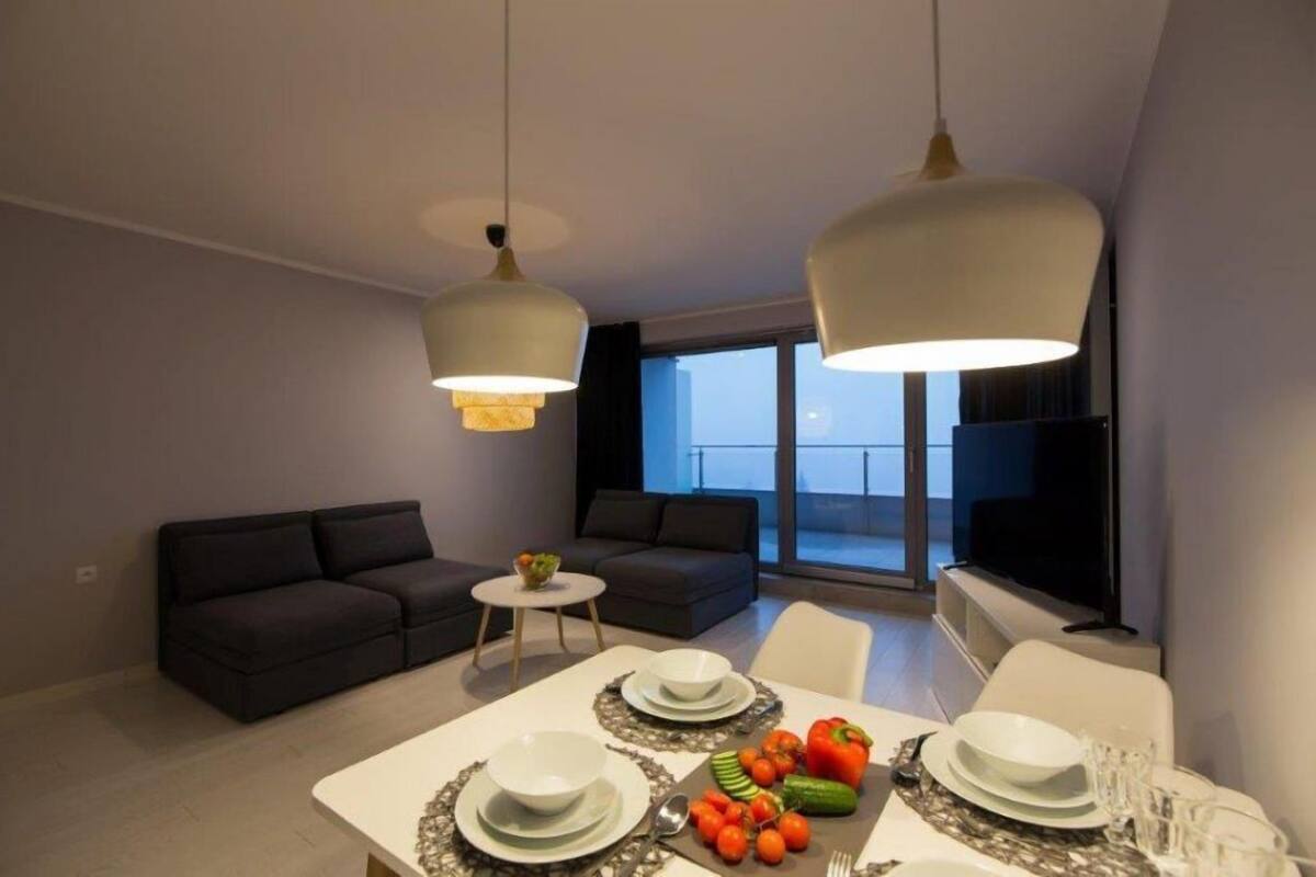 Un salon moderne comprenant un coin repas, deux canapés, une petite table ronde et un téléviseur.