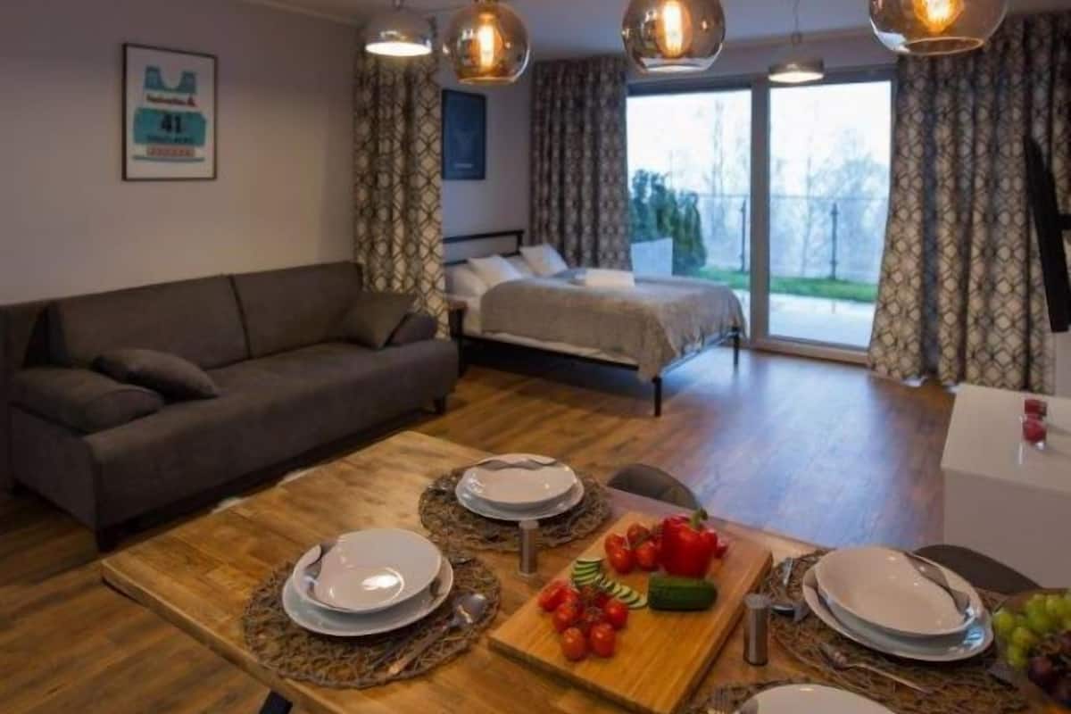 Un salon moderne avec un canapé, une table à manger et des lampes suspendues.