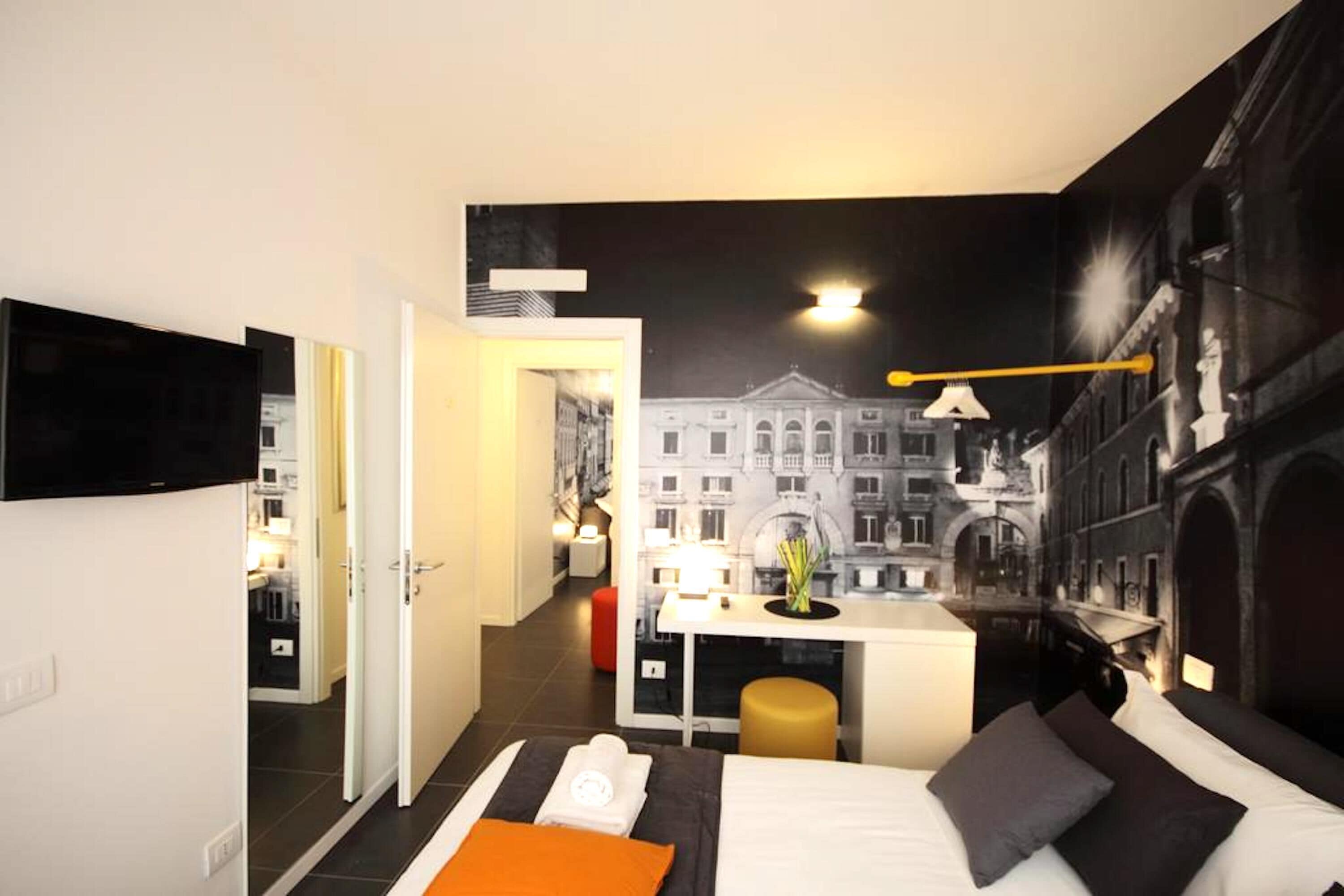 A modern hotel room with a bed, a desk, and a view of a cityscape.