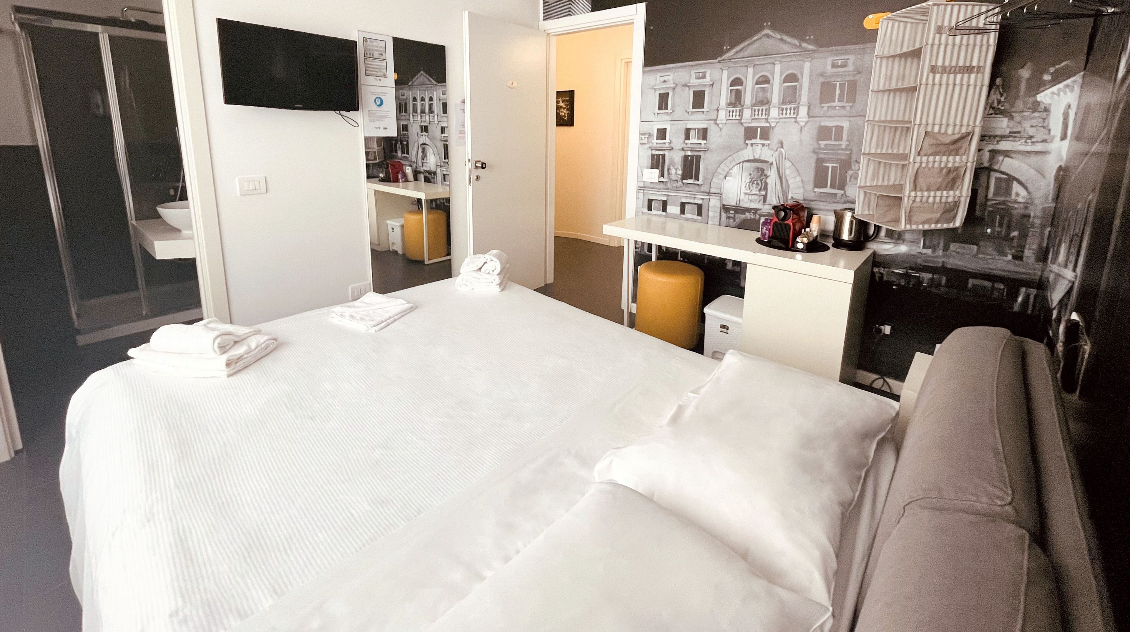 A hotel room with a bed, a desk, a chair, and a bathroom.