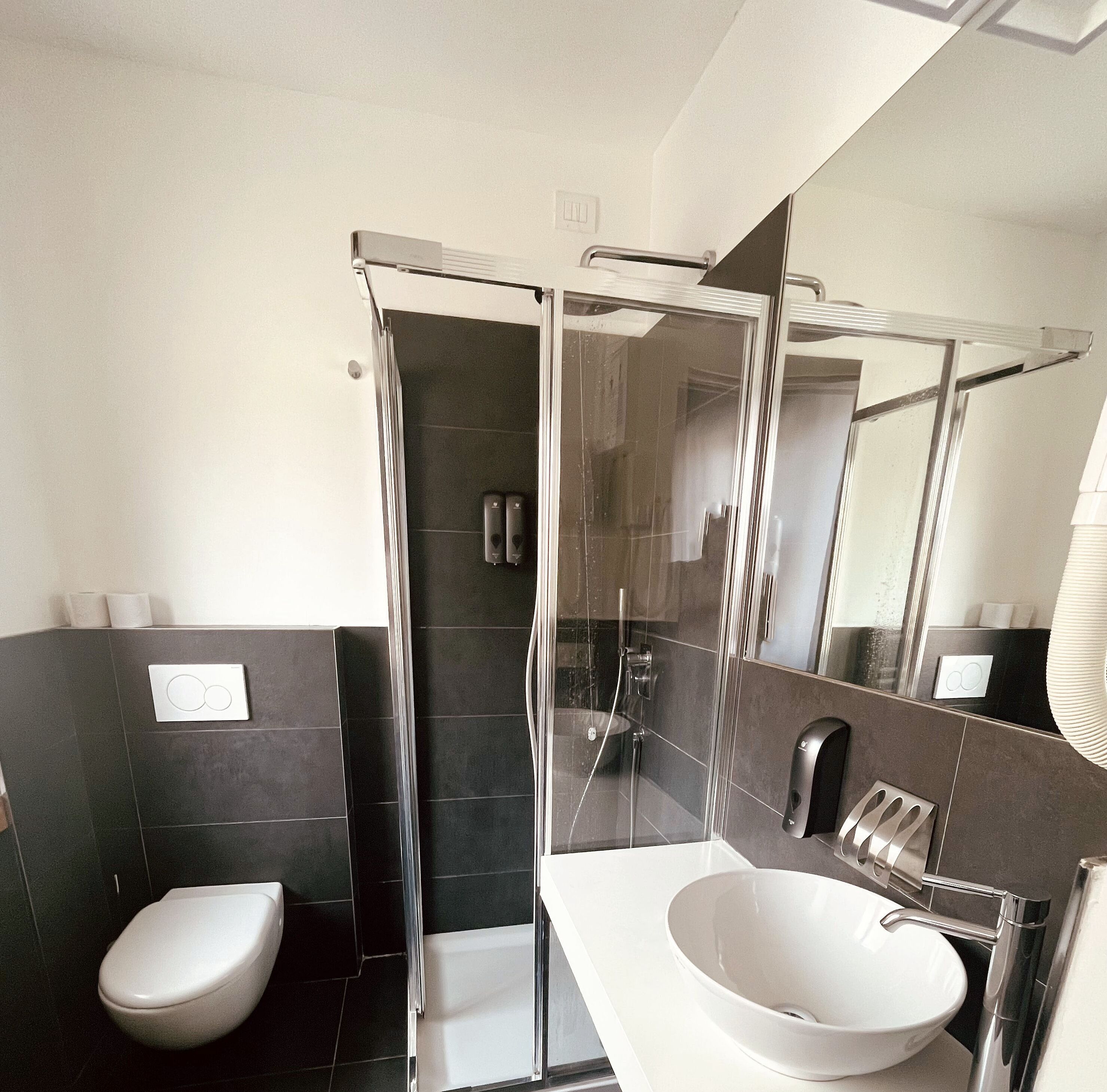 Ein modernes Badezimmer mit einer Duschkabine aus Glas, einem weißen Waschbecken und einer Toilette.