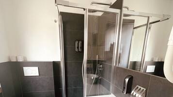 Ein modernes Badezimmer mit einer Duschkabine aus Glas, einem weißen Waschbecken und einer Toilette.