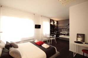 A modern hotel room with a large bed, a desk, a chair, and a TV. - DiMoras House (Verona)