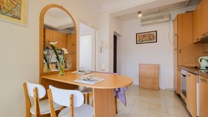 A dining area with a wooden table and chairs, a small kitchen with wooden cabinets, and a map on the wall. - 3rooms downtown Belgrade (Belgrade)