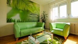 A living room with a green sofa, a glass coffee table, and a fern wall mural. - 3rooms downtown Belgrade (Belgrade)
