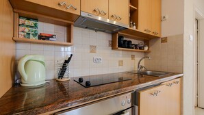 A kitchen with wooden cabinets, a stainless steel range hood, a sink, and a kettle. - 3rooms downtown Belgrade (Belgrade)