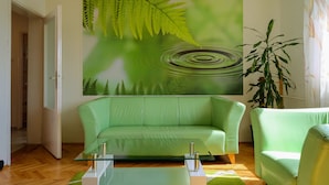 A modern living room with a green sofa, a glass coffee table, and a large fern wall art piece. - 3rooms downtown Belgrade (Belgrade)