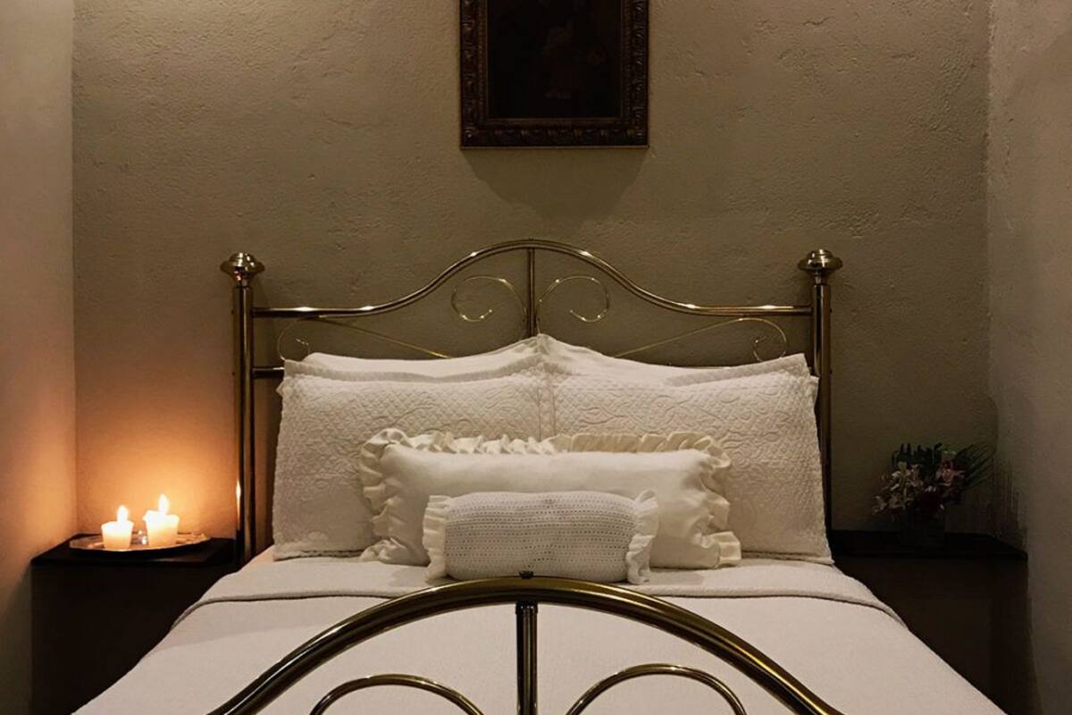 A neatly made bed with a metal frame, white linens, and decorative pillows.