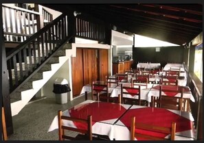 A restaurant with multiple tables and chairs, a staircase, and a trash bin. - Pousada das Flores (Angra dos Reis)