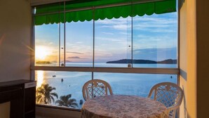 A balcony with a table and chairs, overlooking a body of water and a distant island. - Pousada das Flores (Angra dos Reis)