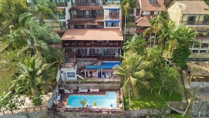 A resort with a swimming pool, multiple balconies, and lush greenery. - Pousada das Flores (Angra dos Reis)