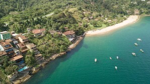 An aerial view of a coastal area with a beach, houses, and boats. - Pousada das Flores (Angra dos Reis)