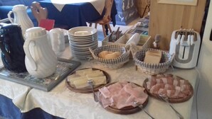 Una mesa de buffet con diversos alimentos, como queso, jamón y pan.