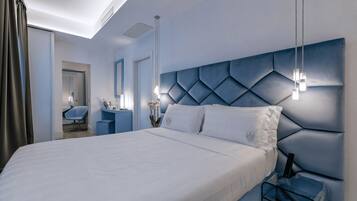 Une chambre d’hôtel moderne avec un grand lit, une tête de lit bleue, un bureau avec une chaise et un miroir.