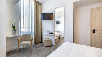 Ein Hotelzimmer mit Bett, Stuhl, Schreibtisch, Fernseher und Bad.
