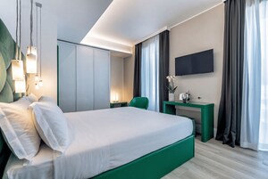 Una habitación de hotel moderna con una cama grande, un escritorio, un televisor de pantalla plana y una pared de acento verde.