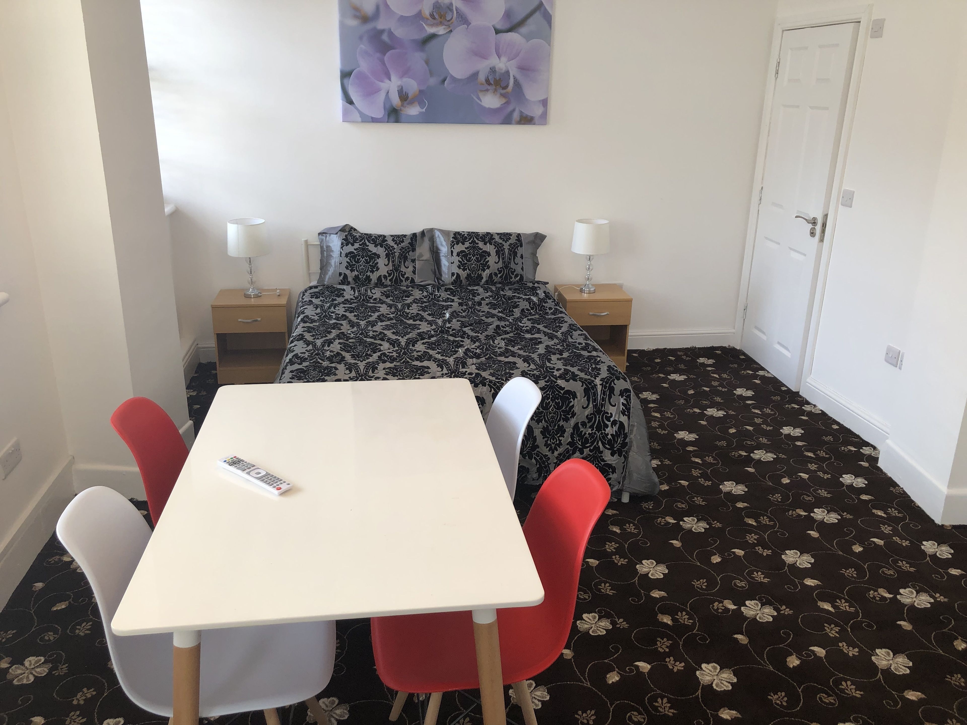 Een kleine, verzorgde kamer met een bed, een tafel en twee stoelen.