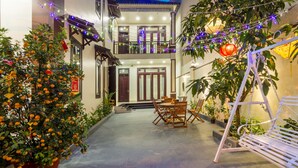 A courtyard with a dining area, a swing, and potted plants. - Gia Phat Homestay  (Da Nang)