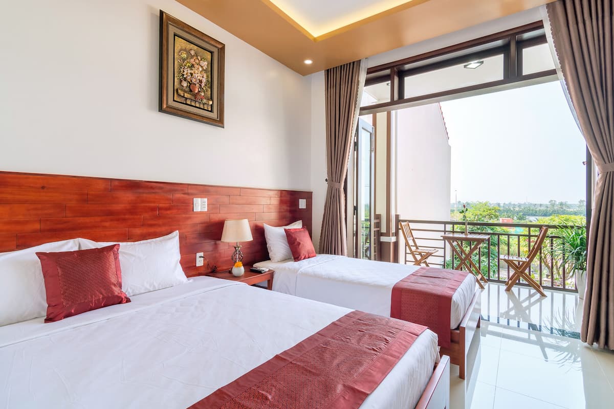 A hotel room with two beds, a wooden headboard, a nightstand with a lamp, and a balcony with a view.