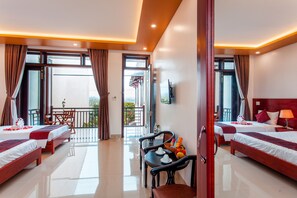 A hotel room with two beds, a balcony, a dining area, and a TV. - Gia Phat Homestay (Da Nang)