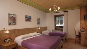 Habitación de hotel con dos camas, cabeceros de madera, un escritorio de madera, una silla y una ventana con cortinas.