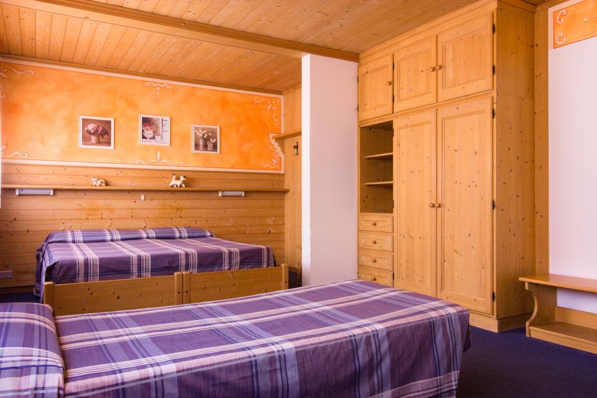 A room with two beds, wooden cabinets, and a wall with pictures.