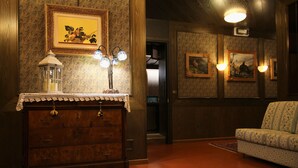 Un aparador de madera con un cubre de encaje, un tapete estampado e iluminación montada en la pared.