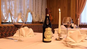Una mesa lista para comer con una botella de Masi Costasera Amaro Classico 2012, dos copas de vino, una vela y un florero con flores.
