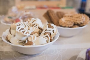 Un bol de postre con glaseado blanco y trozos marrones, y un plato de galletas al fondo.