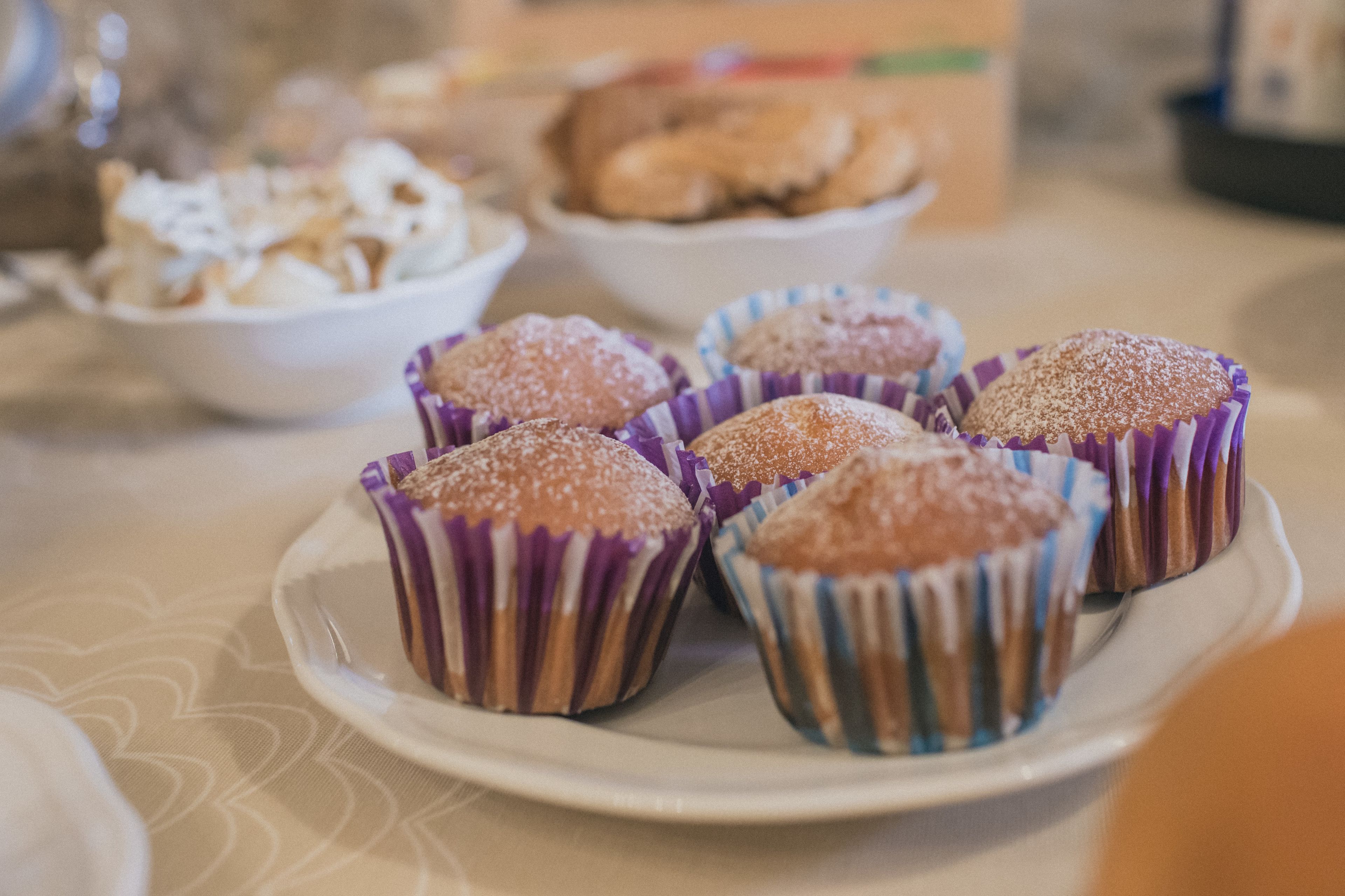 Ein Teller mit Muffins und Puderzucker auf einem Tisch.
