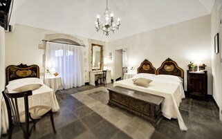 Habitación de hotel con dos camas, un escritorio, una silla, un candelabro y un espejo grande.