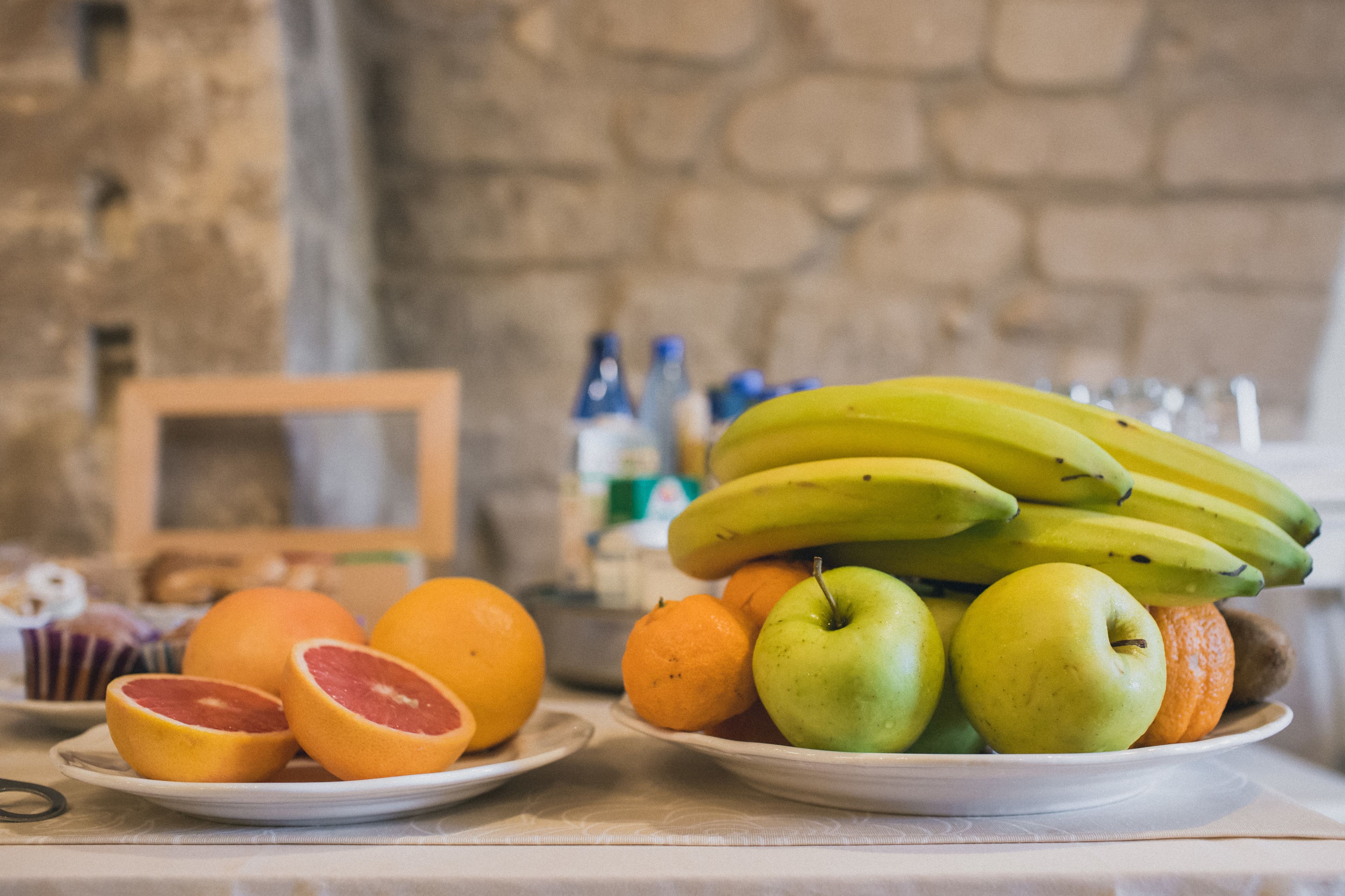 Una mesa con platos de frutas, como plátanos, manzanas y naranjas.