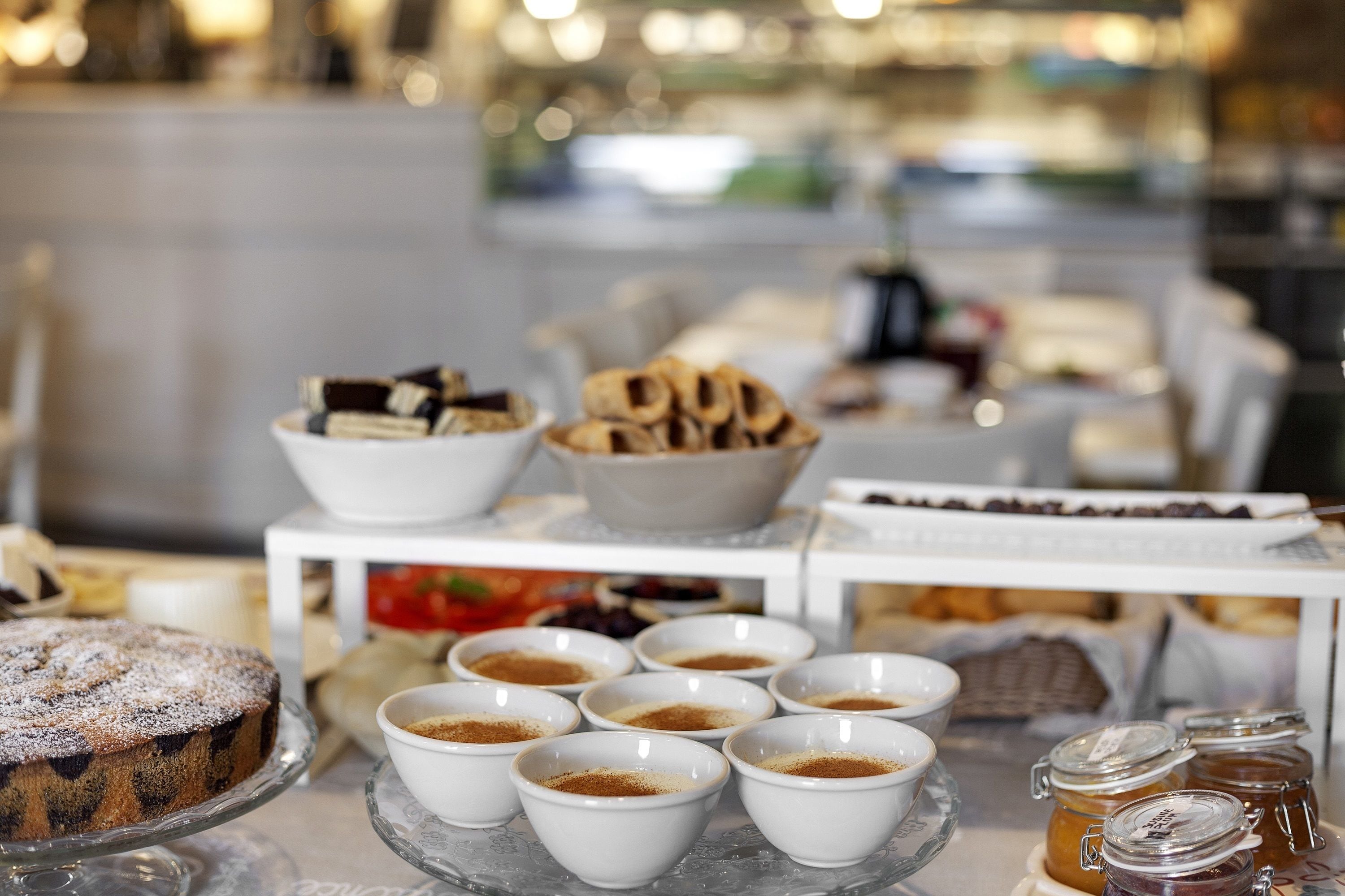 A buffet table with various food items including a cake, bowls of what appears to be a powdered substance, and jars of preserves.